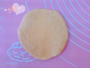 取松弛好的面团用手按扁，挤出大气泡。