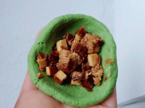 揪一团搓成球，两边薄中间厚，往里面填上馅料。