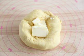 将室温软化的黄油裹进面团里，不断的朝中间包裹揉搓，一开始面会变得散烂油腻，大约揉2-3分钟后，黄油就会被逐渐吸收。