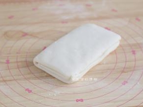 将1/3的面片折下再盖上另一个1/3的面片，就完成了第一次折叠，盖上保鲜膜松弛15-25分钟。