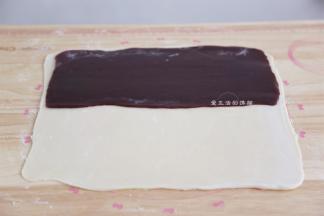将擀成长方形的玫瑰豆沙放入面片里面，上下覆盖住豆沙，边缘稍捏紧，烤箱此时开始上下管180度预热。