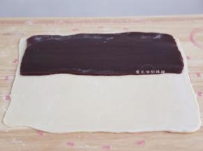 将擀成长方形的玫瑰豆沙放入面片里面，上下覆盖住豆沙，边缘稍捏紧，烤箱此时开始上下管180度预热。