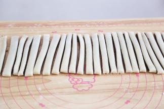 用锋利的刀将面片切成宽度1CM的小条，两手捏起两端，旋转几圈，酥条初胚就做好了，做好的初胚放入垫了油纸的烤盘里。