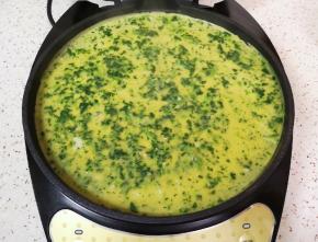 倒入菠菜蛋液，来回晃一下电饼铛，让蛋液铺满电饼铛底部，保证做出来的蛋饼薄厚均匀。