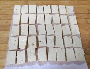 案板上铺上厨房用纸，放上用淡盐水浸泡过的豆腐。