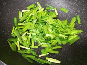 将煎豆腐剩余的油继续加热，下入韭菜翻炒至变色。
