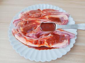 用勺子在羊小排上面淋上酱汁。