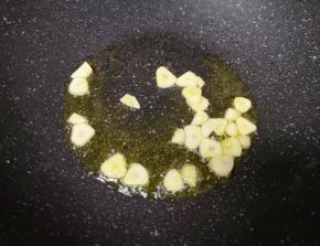 炒锅内继续倒入食用油烧热，下入蒜片爆香。