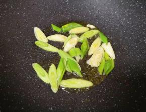 炒锅内倒适量的食用油烧热，下入蒜苗炒香。