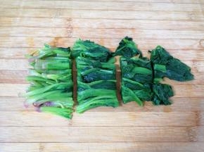 过过凉水的菠菜挤干水分，切成几段。