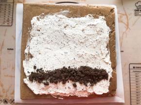 蛋糕胚烤好后撕掉油纸，换一张新油纸，抹上淡奶油再放一点奥利奥饼干碎