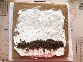 蛋糕胚烤好后撕掉油纸，换一张新油纸，抹上淡奶油再放一点奥利奥饼干碎