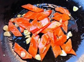 锅中倒入底油加热放入蒜爆香再放入胡萝卜片炒至断生