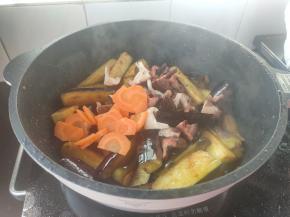 接着加入备好的香菇块、胡萝卜片，再淋上一勺味达美尚品金标生抽，炒匀。