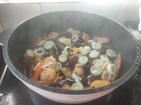 倒入小丸子，简单翻炒均匀，再加入小半碗清水，撒上葱花，盖好盖子转小火焖炖五分钟左右。