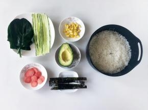 蒸米饭的时候，把配料准备好。黄瓜用刮皮刀削成长条，玉米剥好，水果胡萝卜和牛油果去皮切成薄片，海苔剪成长条。