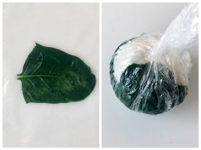 取一片菠菜叶，正面朝下铺平，然后放上饭团，用保鲜膜裹好。