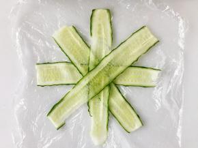 黄瓜条摆成米字型，然后放上饭团裹好。