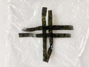 海苔条摆成井字型，然后放上饭团裹好。