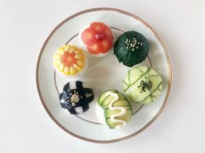 揭掉保鲜膜，在胡萝卜花中间点上番茄酱，牛果油上挤上沙拉酱，菠菜、黄瓜和海苔的饭团面上分别用黑、白熟黑芝麻装饰。