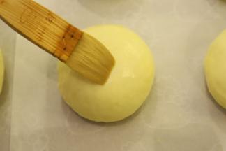 预热烤箱180度，取出面包胚，表面刷上蛋黄液。