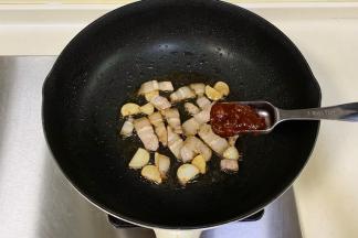 锅中倒入食用油，先入蒜片爆香，加入五花肉翻炒至变色，加入辣味黄豆酱。