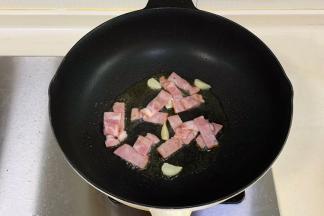 锅中倒入橄榄油，先放入蒜片爆香，加培根炒至微焦，盛出。
