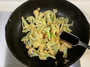 锅中倒入花菜翻炒至变软微焦，加生抽和蚝油翻炒。