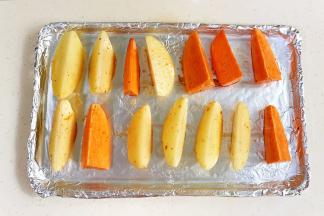 烤盘上铺上锡纸，把土豆和红薯摆入，中间留有间隙。