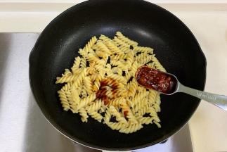 把意面入锅，加生抽、蚝油和辣味黄豆酱炒匀。