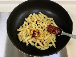 把意面入锅，加生抽、蚝油和辣味黄豆酱炒匀。