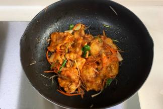 把炸好的肉片入锅，撒入胡萝卜、葱丝和香菜炒匀出锅。