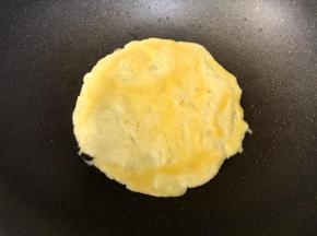 先倒入1/3的蛋液，均匀摊开，煎至7成熟。
