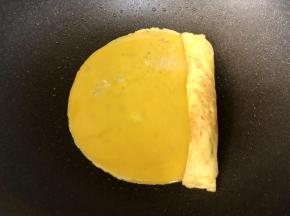 第二次加入蛋液，迅速摊开，让蛋液与蛋卷粘连，煎至7成熟后，继续卷起；