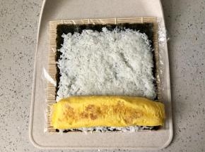 然后把煎好的厚蛋烧放在米饭的一端；