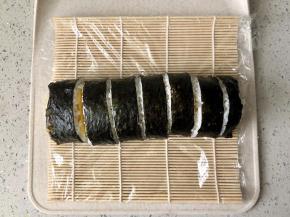 打开寿司席，用寿司刀把寿司卷切成等宽的小段，每切一下都要把刀擦干净再切下一刀，这样能保证每一个寿司都比较美观。