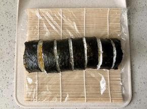打开寿司席，用寿司刀把寿司卷切成等宽的小段，每切一下都要把刀擦干净再切下一刀，这样能保证每一个寿司都比较美观。