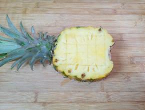 先来处理菠萝，将菠萝从叶子下面的三分之一处切开，少的一半去皮只取菠萝果肉，带叶子的一半用水果刀划十字，用勺子挖出菠萝果肉。
