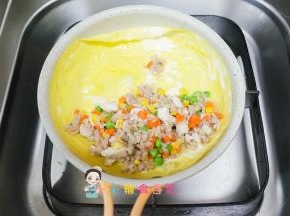 把刚才混合好的鸡肉蔬菜饭放到鸡蛋皮上