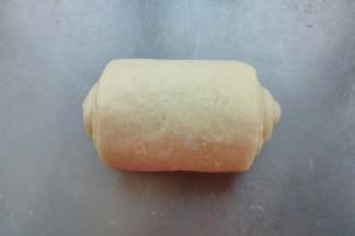 取出卷好的面团，再次轻轻的擀成长舌状，边缘有气泡的话用手拍掉，翻面，从上往下卷。