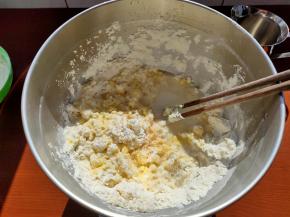 用筷子简单搅拌成絮状，再加入清水，用筷子搅拌，让面团大致成形，可以用手或者用刮刀把面团都按压在一块。