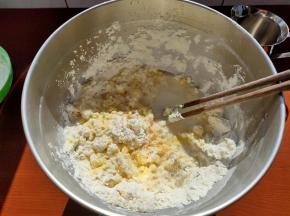 用筷子简单搅拌成絮状，再加入清水，用筷子搅拌，让面团大致成形，可以用手或者用刮刀把面团都按压在一块。