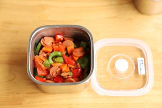 准备两个便当，将炒好的火腿肠彩椒放入便当内铺平。