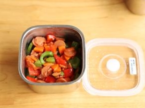 准备两个便当，将炒好的火腿肠彩椒放入便当内铺平。