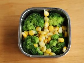 另一个便当里面铺上蛋黄饭，四周各放一个西兰花，放入玉米粒。
