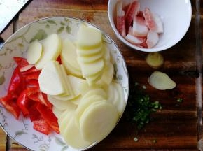 准备材料，土豆去皮清洗干净，切薄片。肉切成肉片清洗干净。红椒去柄去籽清洗干净，切成小块。葱姜清洗干净，葱切成葱花。