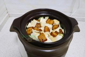 把炒的大白菜，倒入炖砂锅，接着放入煎好的豆腐、五花肉，一小碗高汤，没有高汤就加一小碗沸水。