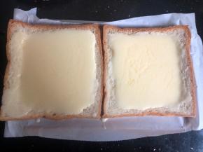 将酸奶蛋液用勺子倒入吐司片上。