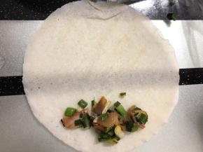 在下边摆上少许大蒜咸肉，如图所示！然后卷起来就可以了。