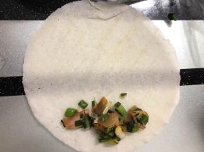 在下边摆上少许大蒜咸肉，如图所示！然后卷起来就可以了。